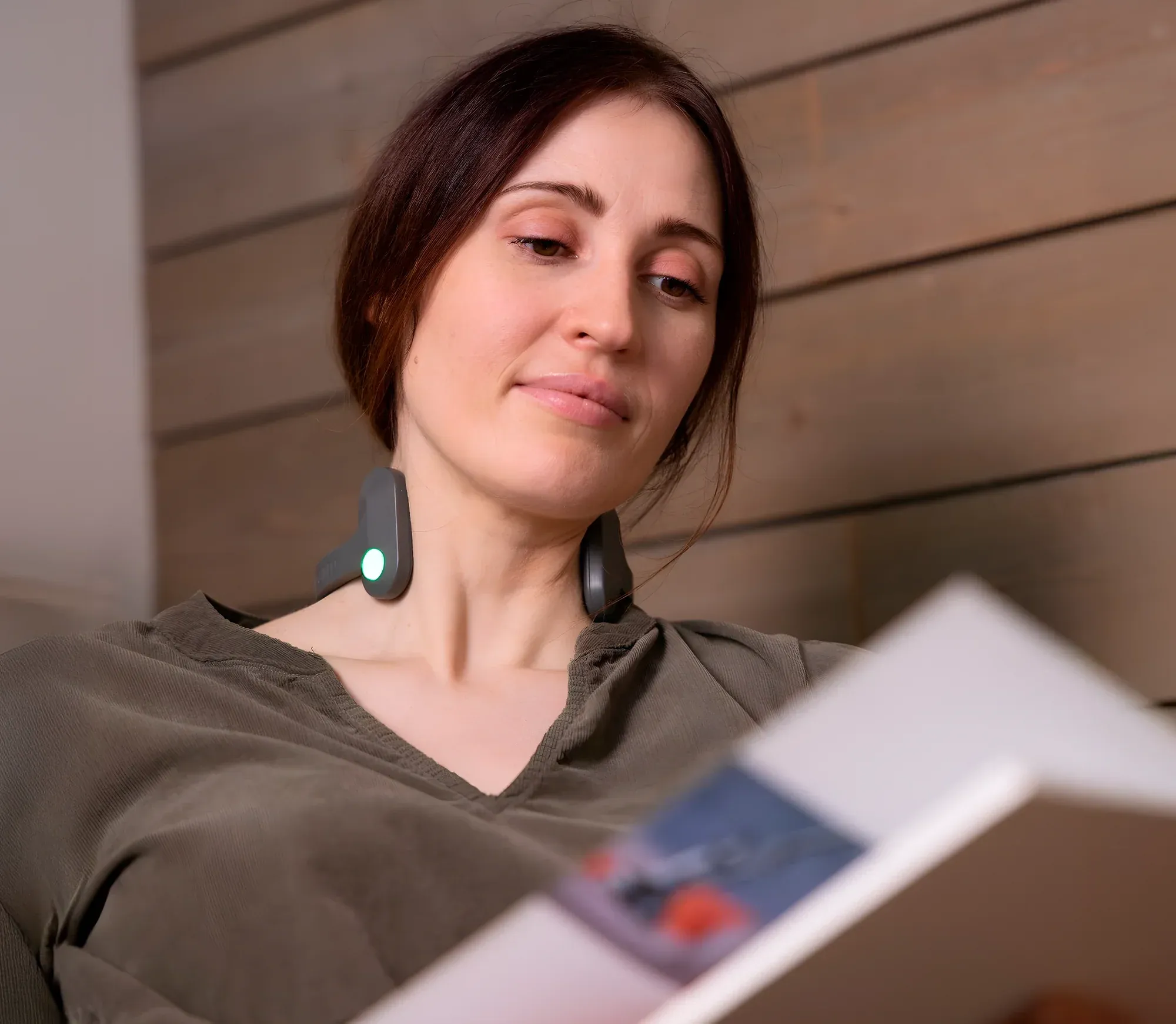 Woman relaxing and reading while wearing Pulsetto FIT